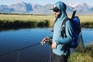 Un ragazzo che pesca sul lago con la maglia 686