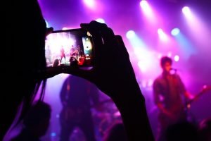 un ragazzo col cellulare riprende un concerto rock