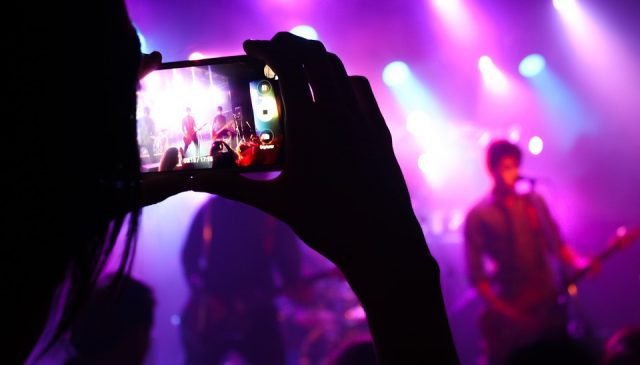 un ragazzo col cellulare riprende un concerto rock