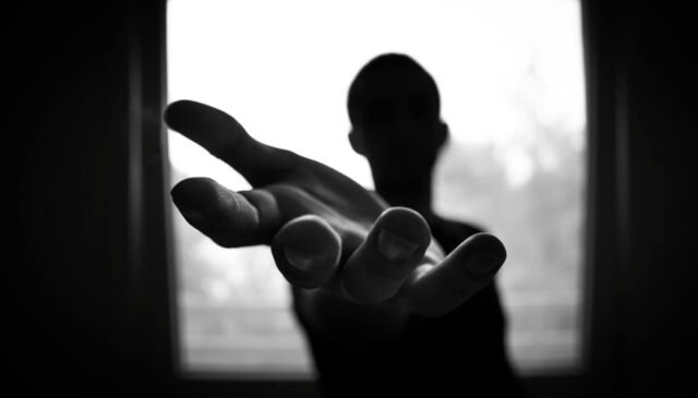 man s hand in shallow focus and grayscale photography