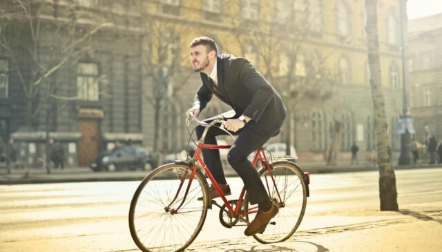 man in black suit riding bicycle down the street