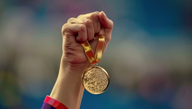 hand of a woman raising an Olympic gold medal in victory