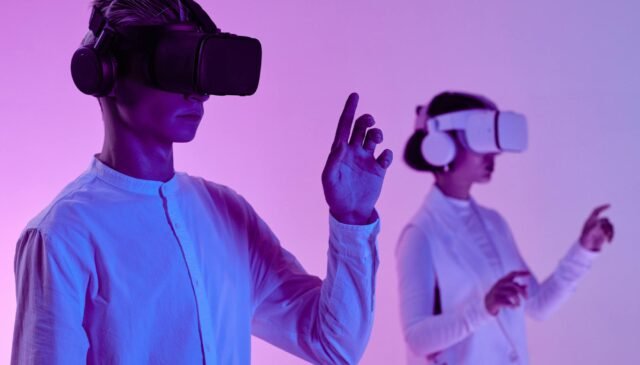 man and woman in vr goggles and headphone standing in studio in purple lighting