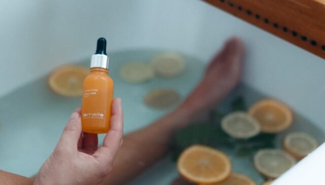 person holding orange and black plastic bottle