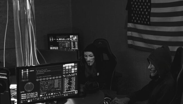 grayscale photo of hackers sitting on chairs