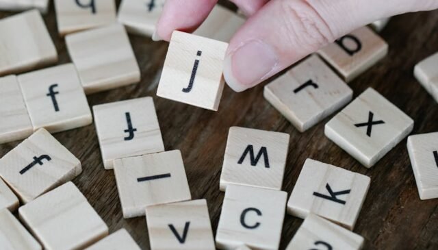 person holding a wooden scrabble tile