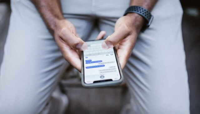 man s thumbs typing on a smartphone
